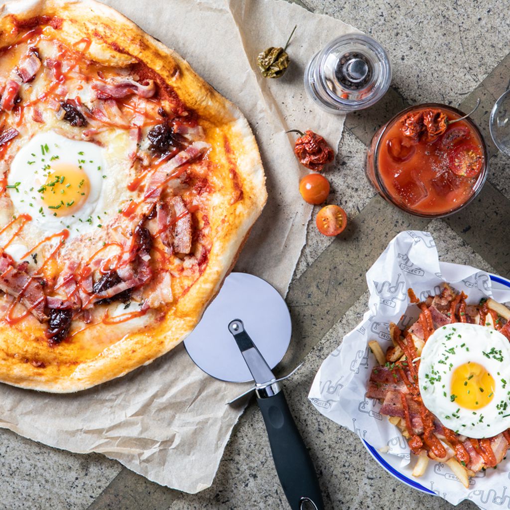 A pizza with a side of chips with bacon topped with fried egg